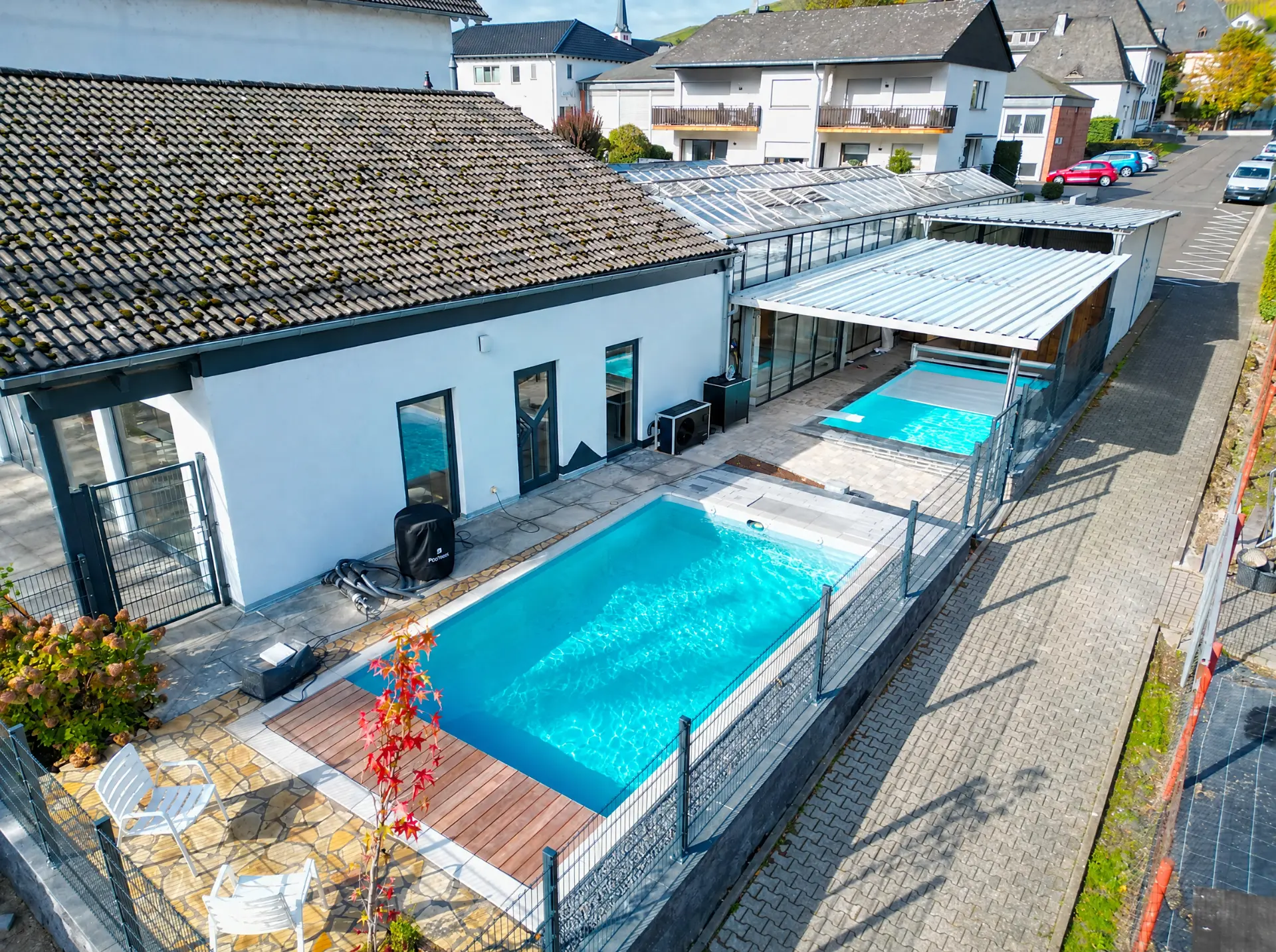 Desjoyaux Pool-Ausstellung von oben: rechteckiges Becken mit türkisfarbenem Wasser, Naturstein-Terrasse und Holzdeck